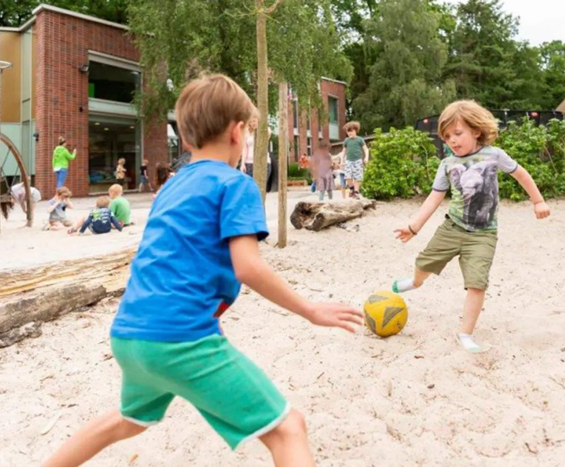 Kinderen spelen met de bal in de buitenruimte bij BSO De Wilde Poema Bilthoven van kinderopvang Kind&co ludens