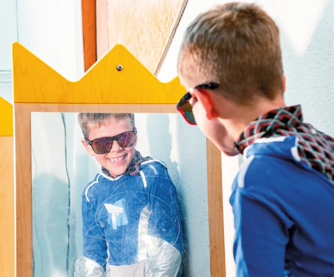 Kind op de BSO heeft veel plezier tijdens een verkleedpartij bij het kijken in de spiegel van kinderopvang Kind&co ludens