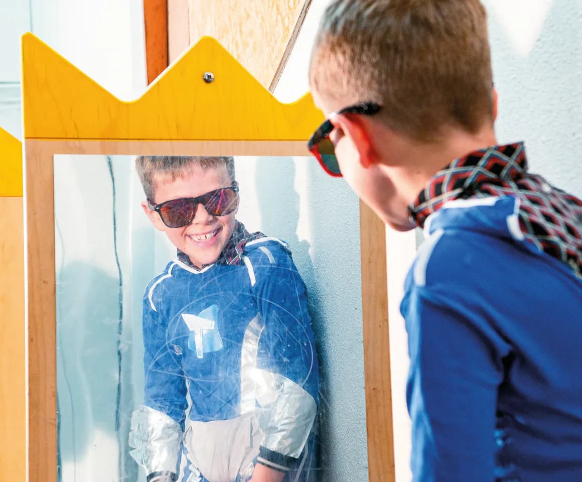 Kind op de BSO heeft veel plezier tijdens een verkleedpartij bij het kijken in de spiegel van kinderopvang Kind&co ludens