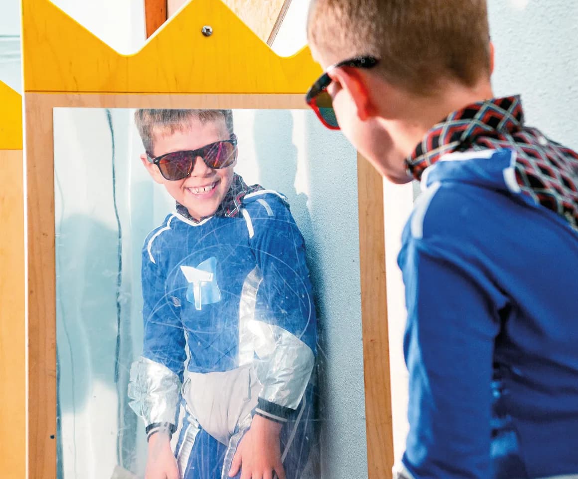 Kind op de BSO heeft veel plezier tijdens een verkleedpartij bij het kijken in de spiegel van kinderopvang Kind&co ludens