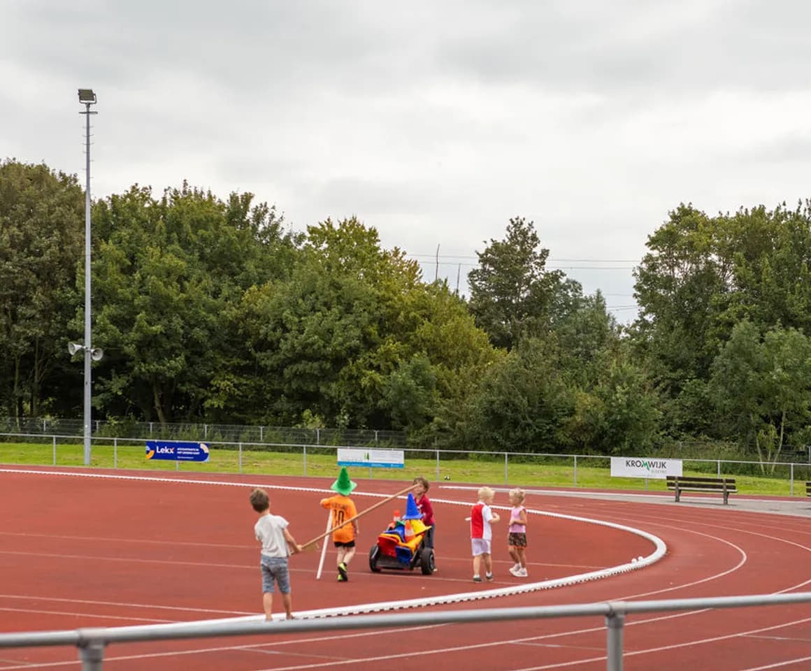 Kinderen verzamelen pionnen op de atletiekbaan van buitenschoolse opvang Asterix en Obelix, kinderopvang Kind&co Ludens