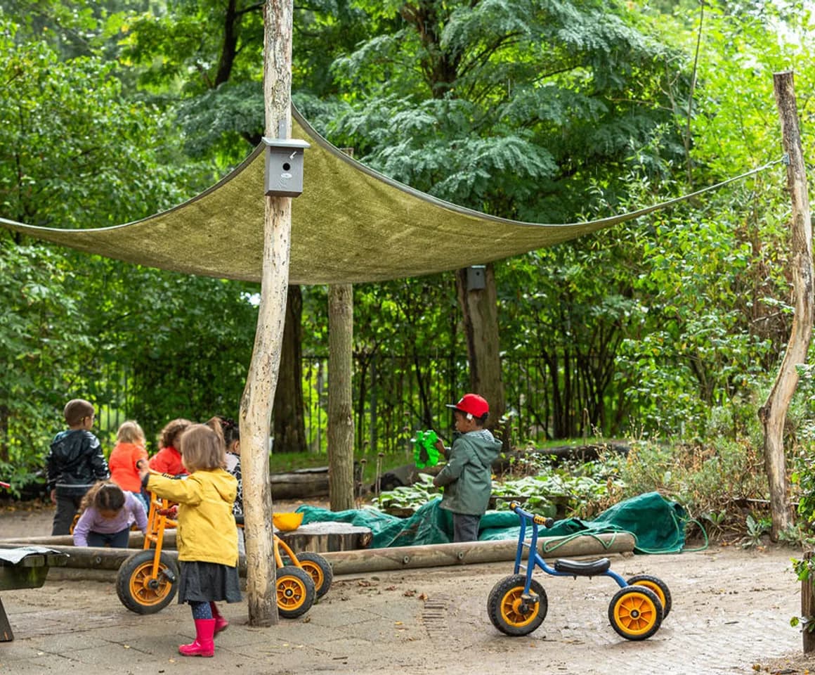Kinderen spelen buiten met fietsjes en in de zandbak bij kinderdagverblijf Hummeltje, Kind&co ludens