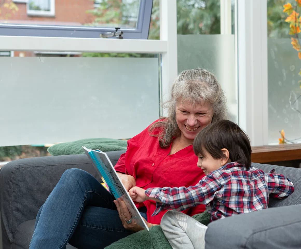 Kind leest boek met pedagogisch medewerker bij buitenschoolse opvang Ay van kinderopvang Kind&co ludens