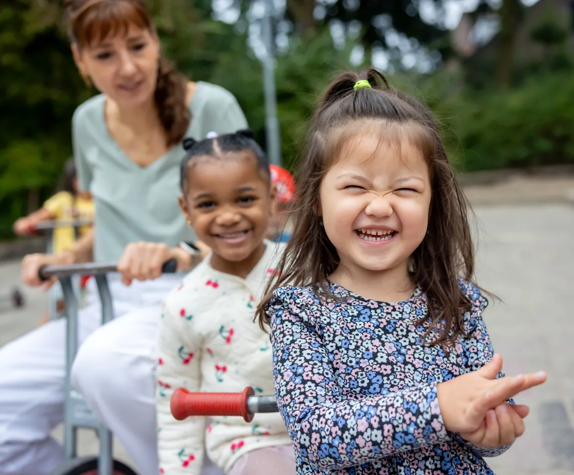 Kinderen spelen buiten met pedagogisch medewerker bij kinderopvang Kind&co ludens