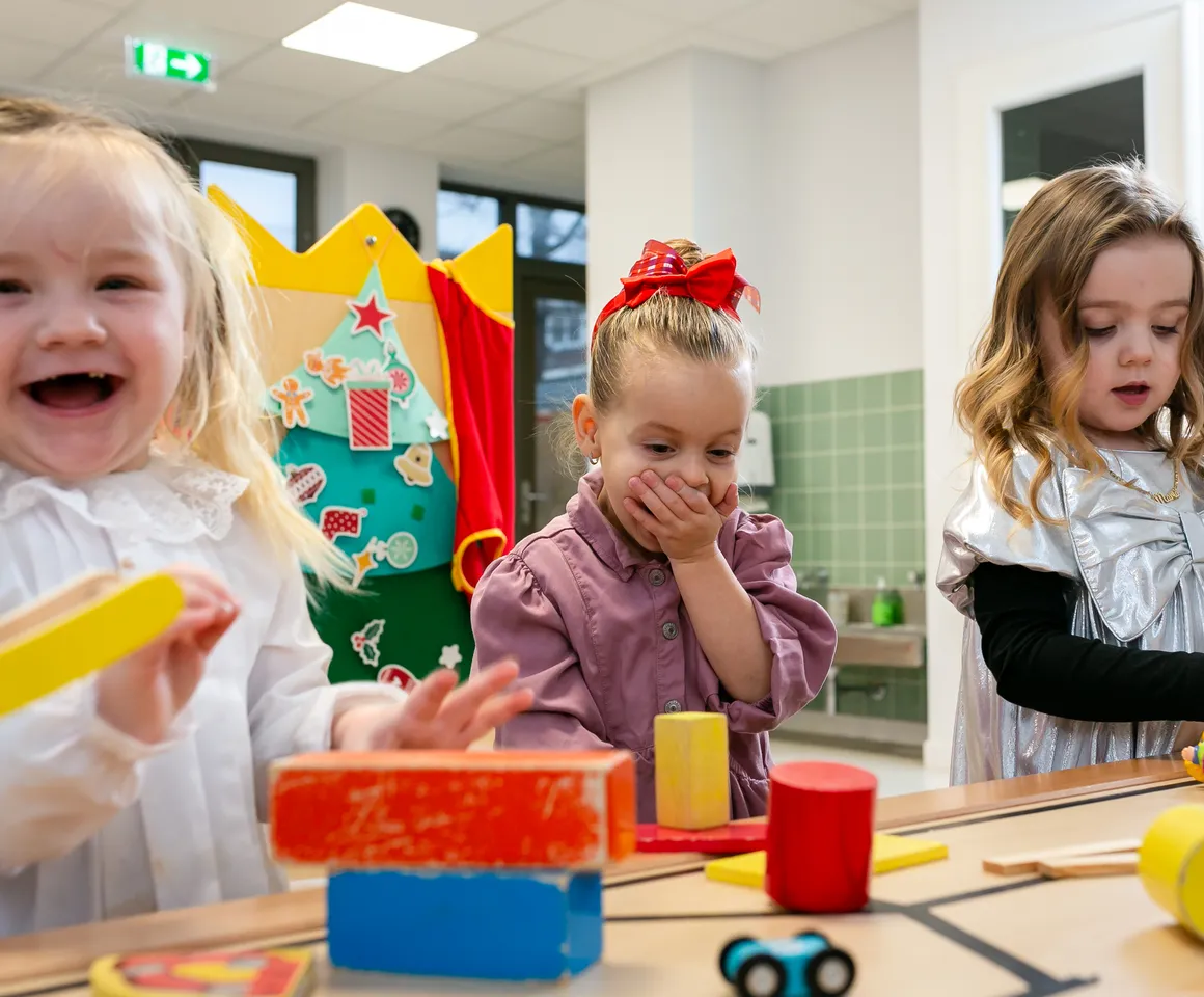 Kinderen van de peutergroep lachen en spelen samen bij kinderopvang Kind&co ludens