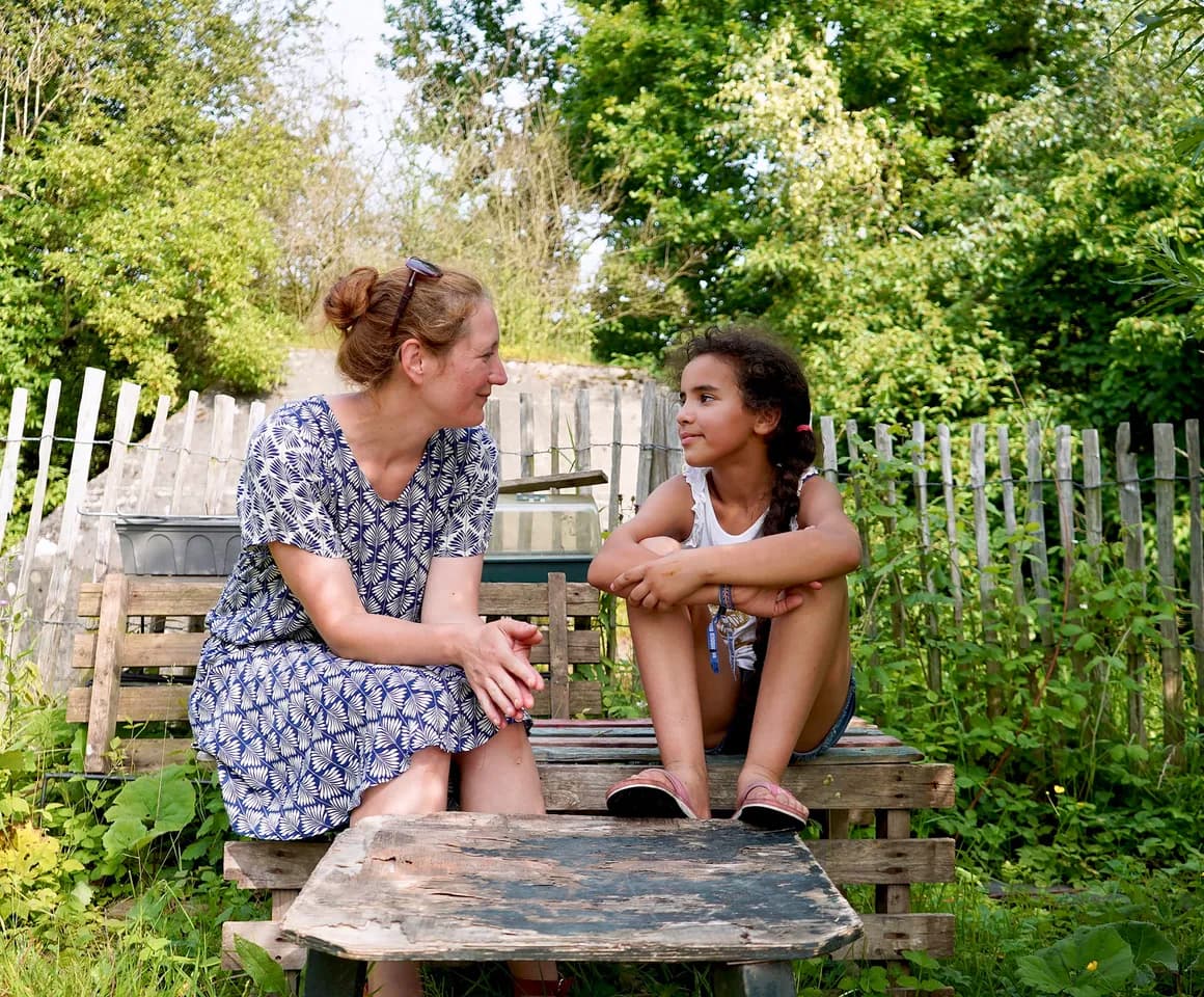 Kind bij de BSO praat buiten samen met de pedagogisch medewerker bij kinderopvang Kind&co ludens