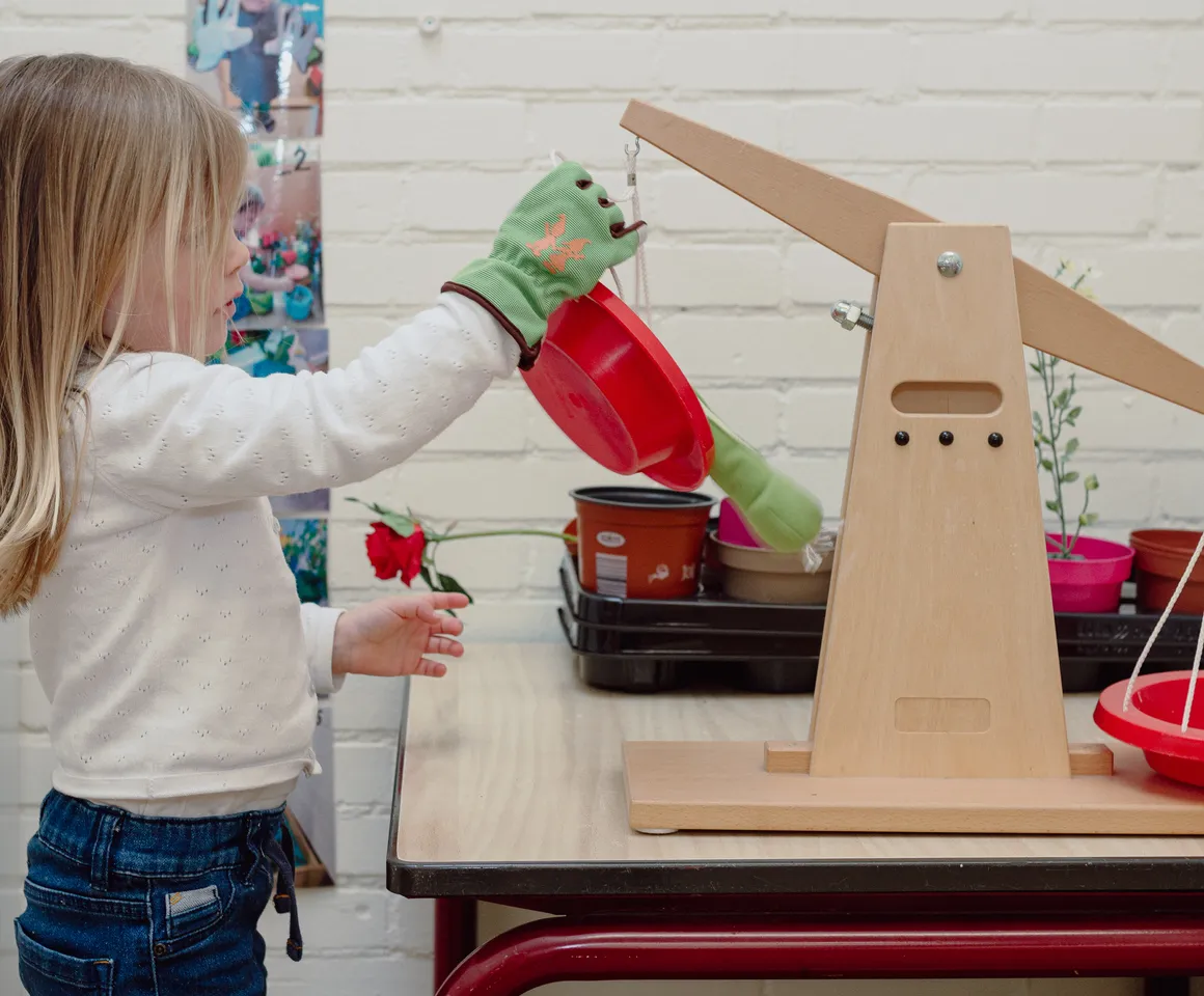 Een kind van de peutergroep speelt met een weegschaal bij kinderopvang Kind&co ludens