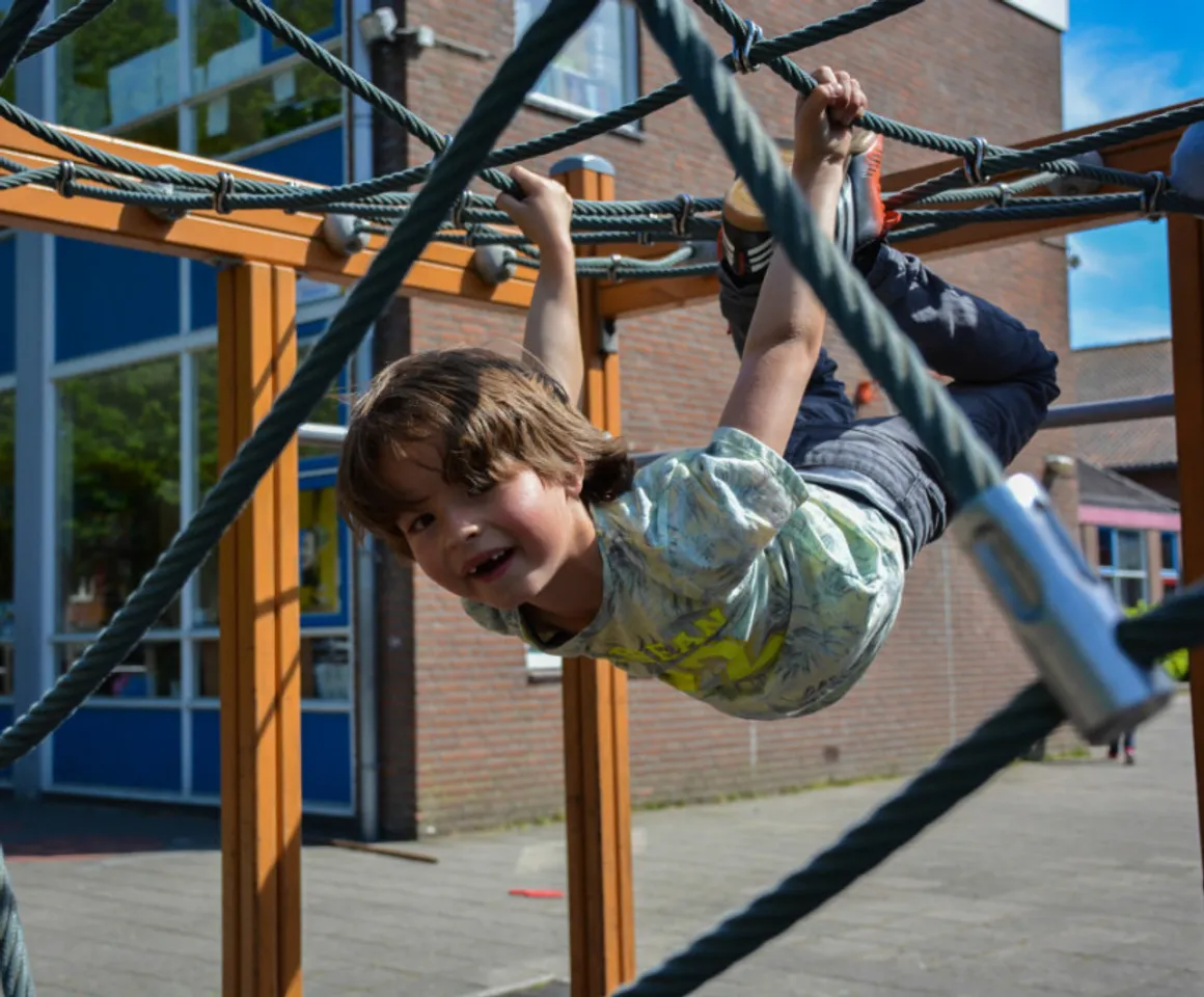 Kind klimt in klimspin bij buitenschoolse opvang spelerij van kinderopvang Kind&co ludens