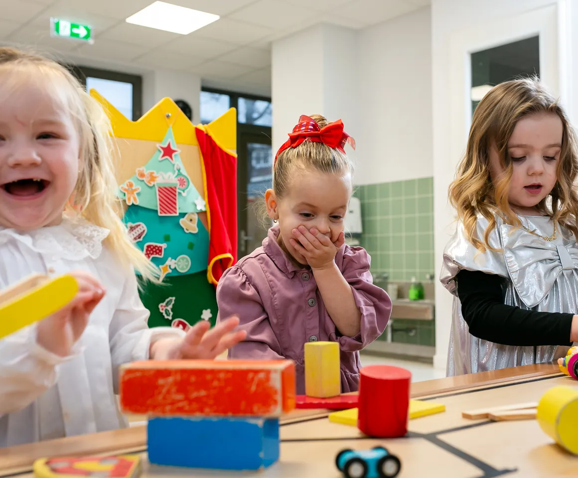 Kinderen van de peutergroep lachen en spelen samen bij kinderopvang Kind&co ludens