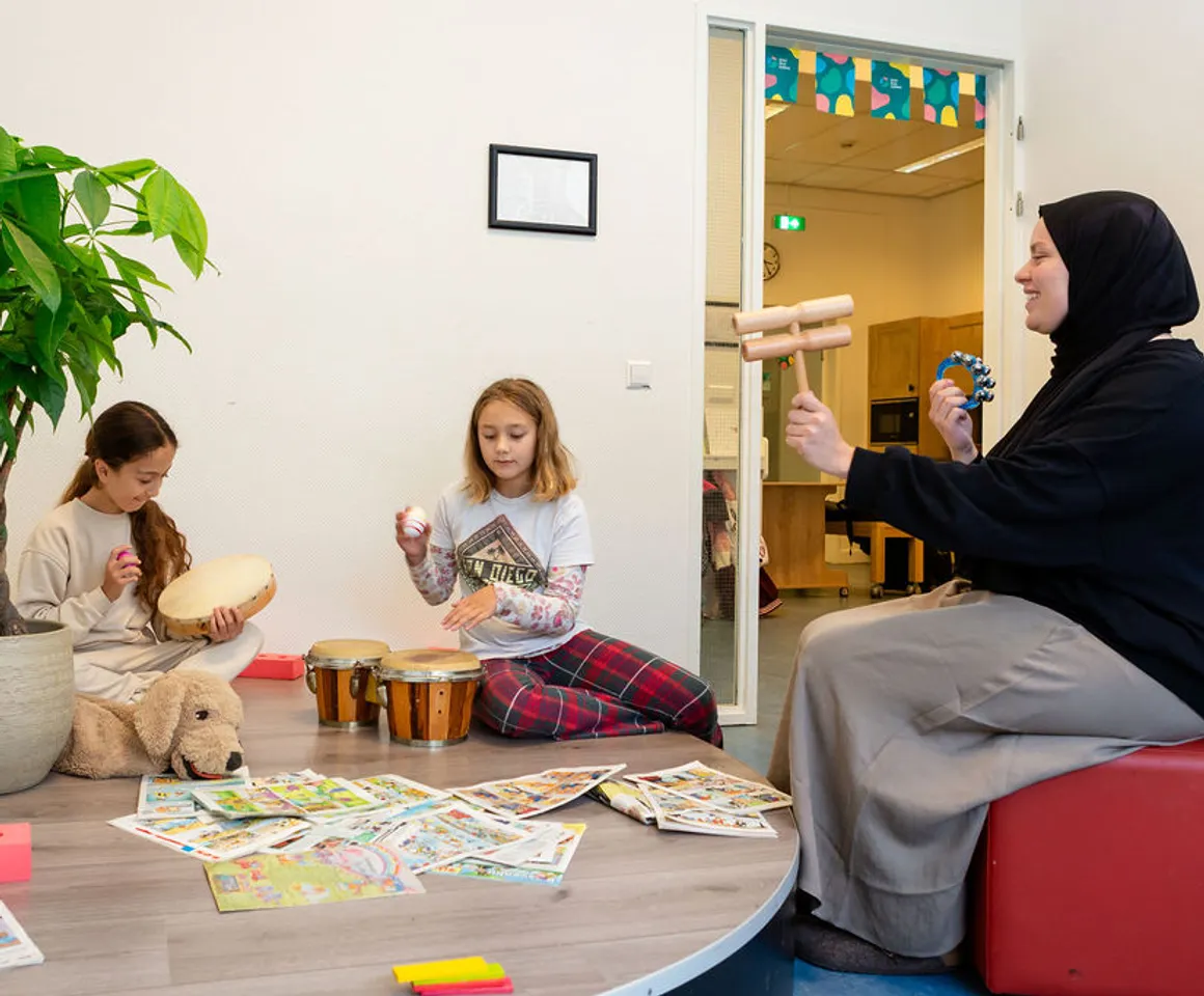 Kinderen maken muziek met pedagogisch medewerker bij kinderopvang Kind&co ludens