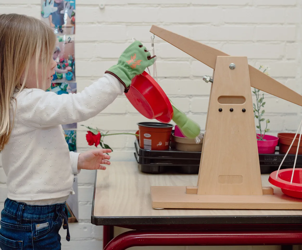 Een kind van de peutergroep speelt met een weegschaal bij kinderopvang Kind&co ludens