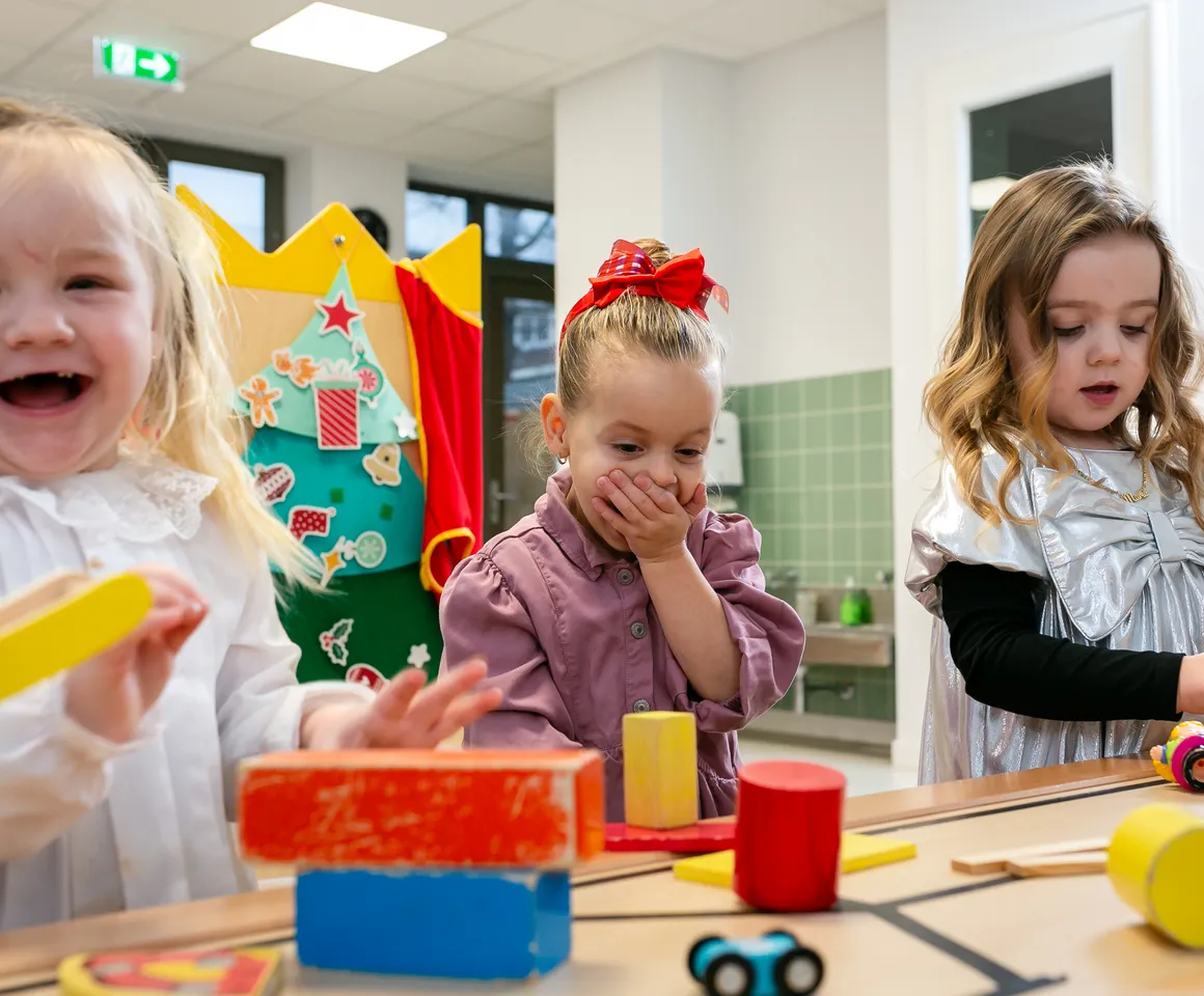 Kinderen van de peutergroep lachen en spelen samen bij kinderopvang Kind&co ludens