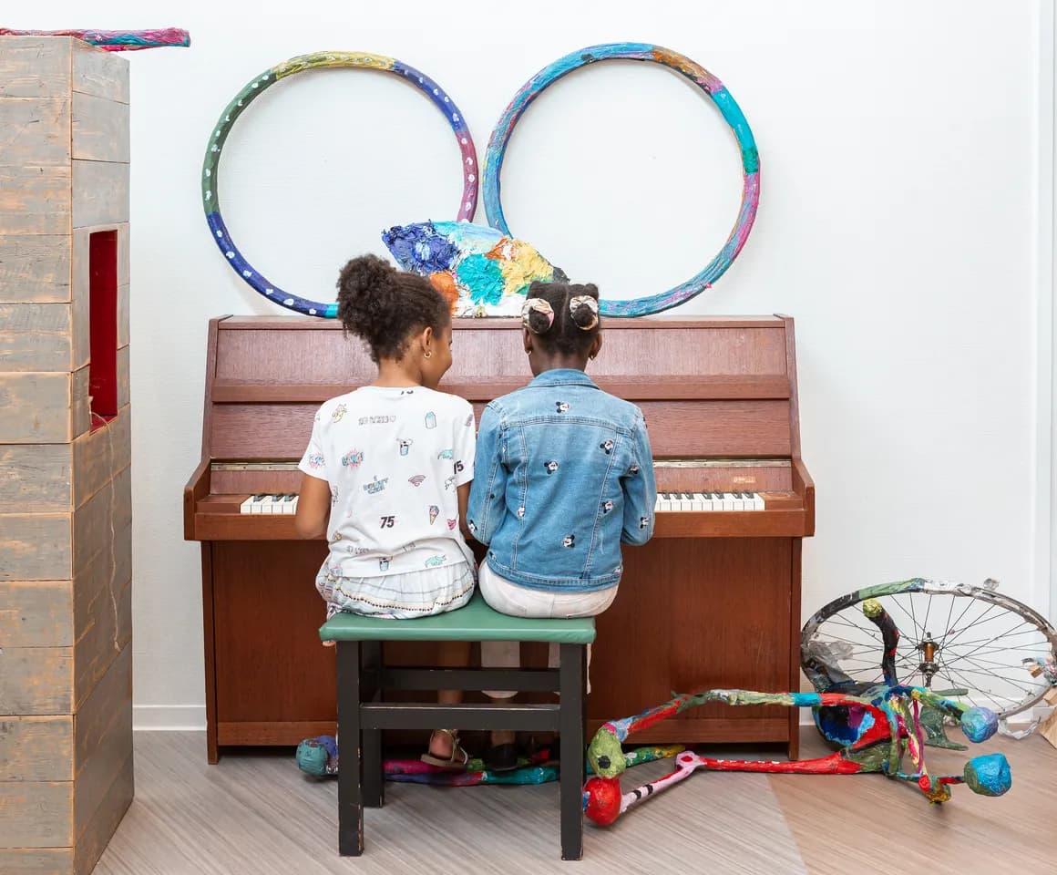 Kinderen spelen samen op de piano bij de BSO van kinderopvang Kind&co ludens