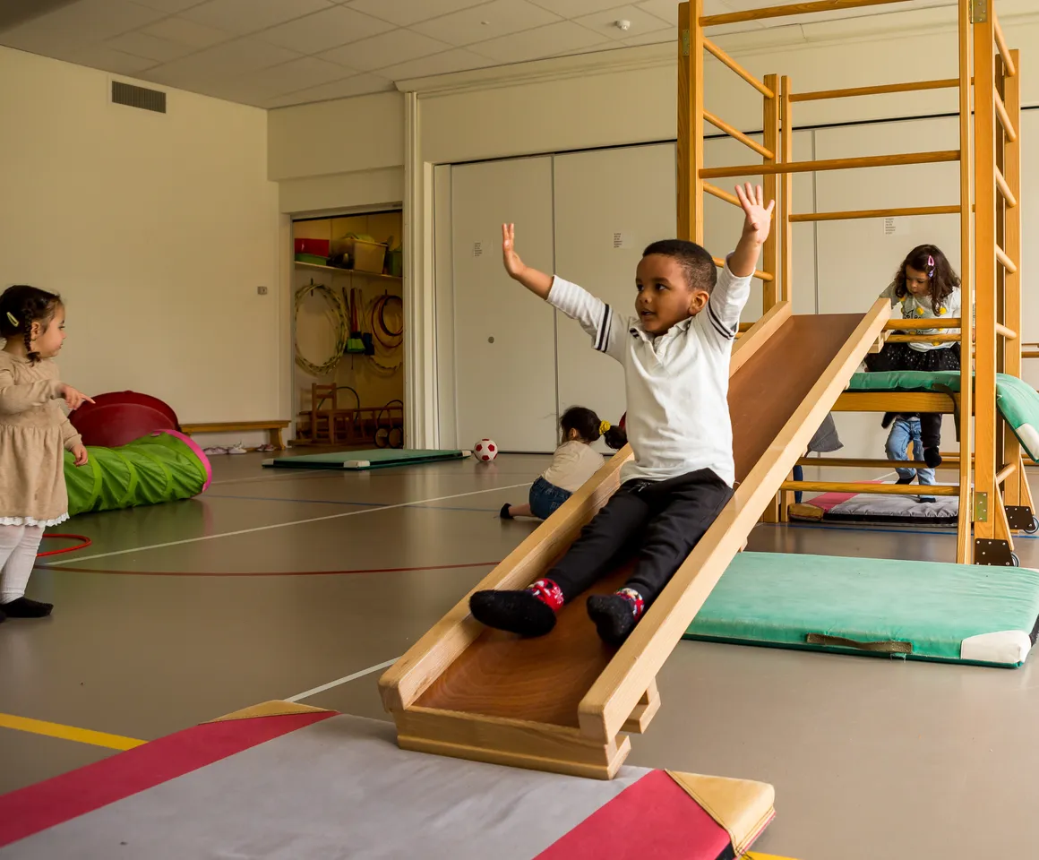 Kinderen klimmen en glijden in gymzaal bij kinderopvang Kind&co ludens