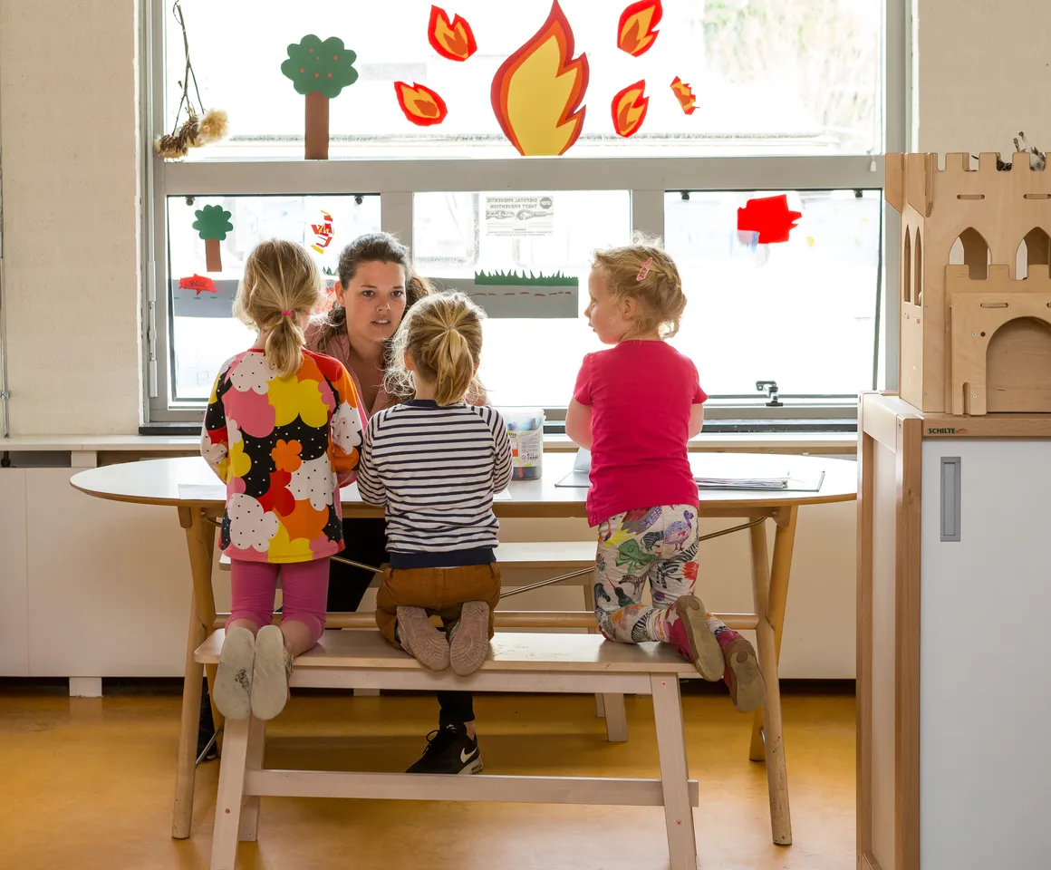 Kinderen samen met pedagogisch medewerker aan tafel bij BSO Utrecht Bolderburen van kinderopvang Kind&co ludens