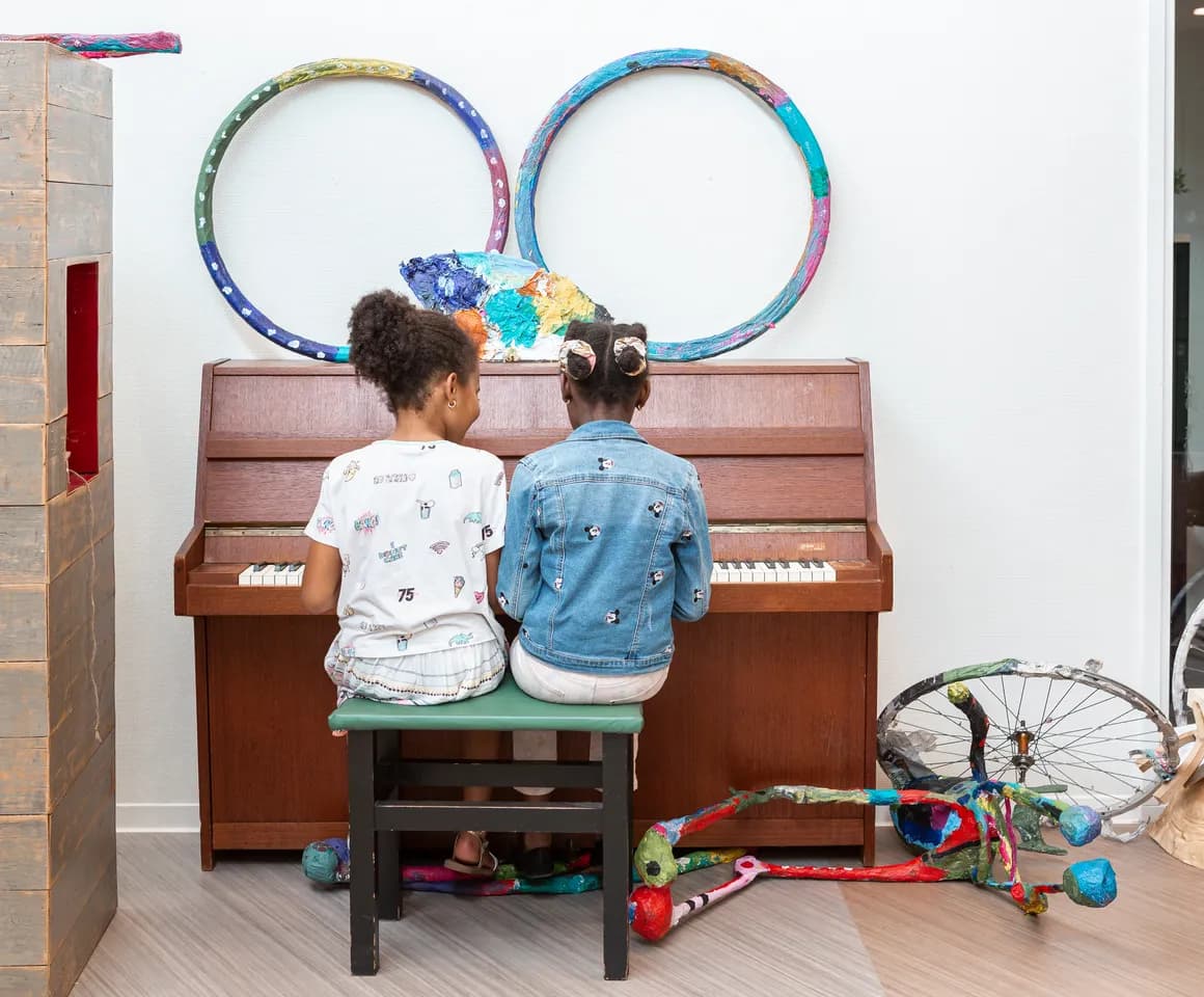 Kinderen spelen samen op de piano bij de BSO van kinderopvang Kind&co ludens