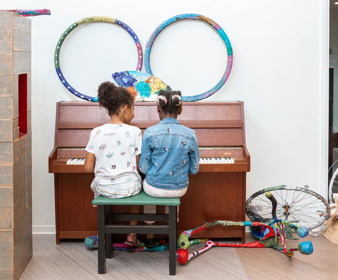 Kinderen spelen samen op de piano bij de BSO van kinderopvang Kind&co ludens