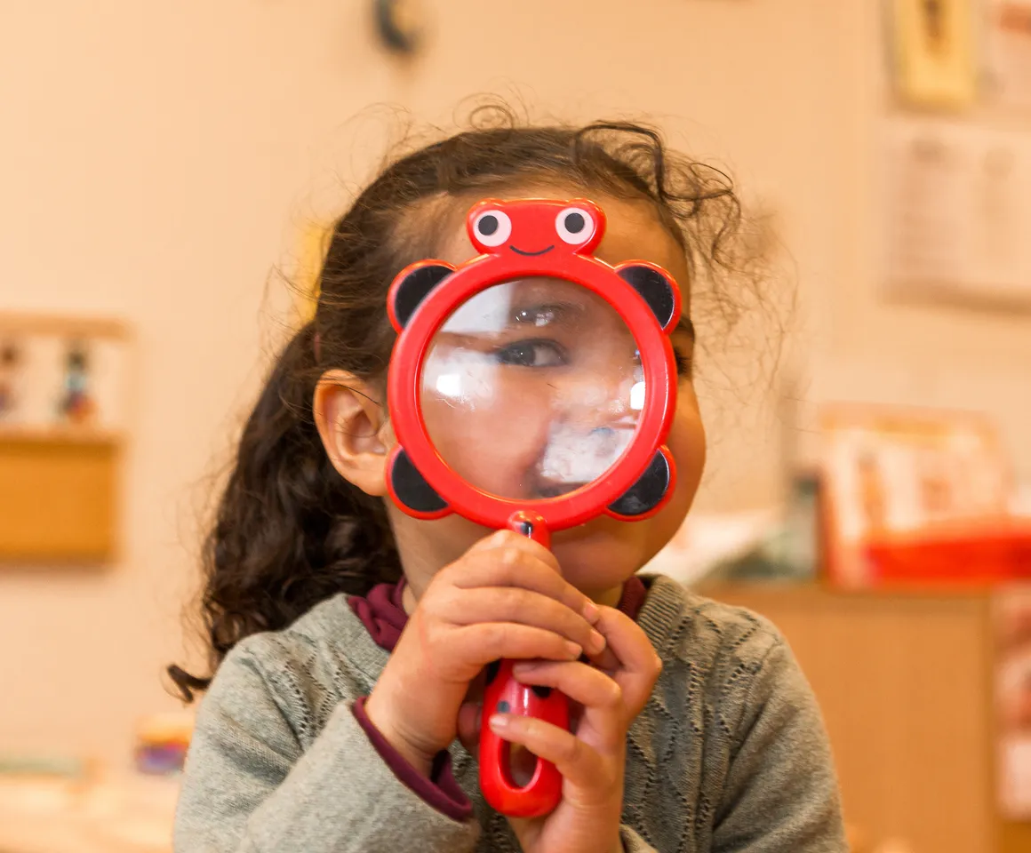 Kind op de peutergroep speelt met vergrootglas bij kinderopvang Kind&co ludens