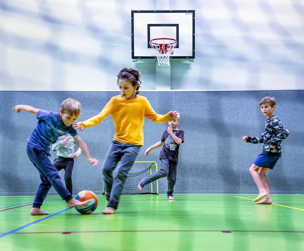 Kinderen van de BSO spelen samen voetbal in de gymzaal bij kinderopvang Kind&co ludens