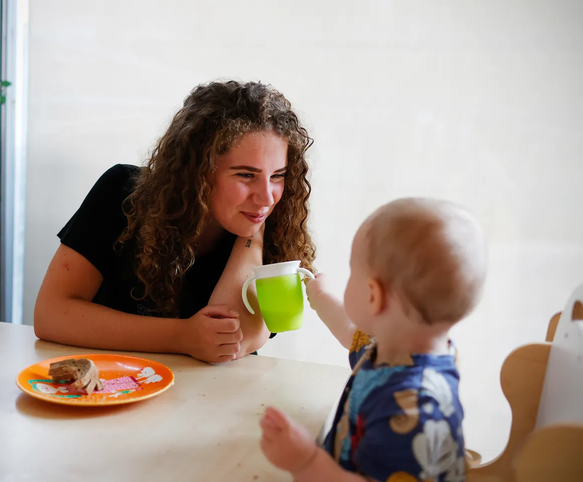 Kind eet samen met pedagogisch medewerker bij kinderopvang Kind&co ludens