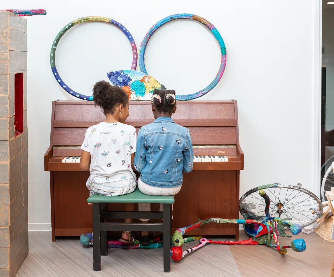 Kinderen spelen samen op de piano bij de BSO van kinderopvang Kind&co ludens