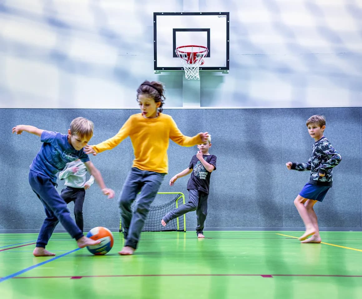 Kinderen van de BSO spelen samen voetbal in de gymzaal bij kinderopvang Kind&co ludens