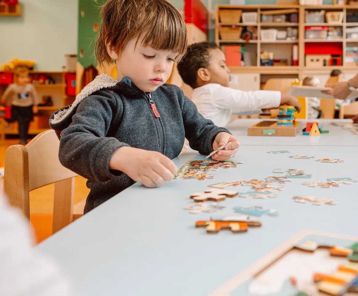 Kinderen puzzelen aan tafel bij peuteropvang Kadodder, Kind&co ludens