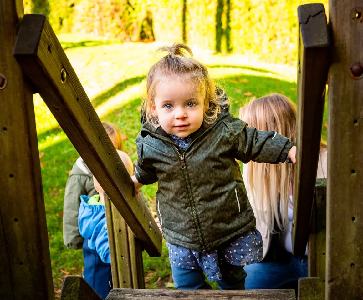 Kind speelt buiten op een speeltoestel bij kinderopvang Kind&co ludens