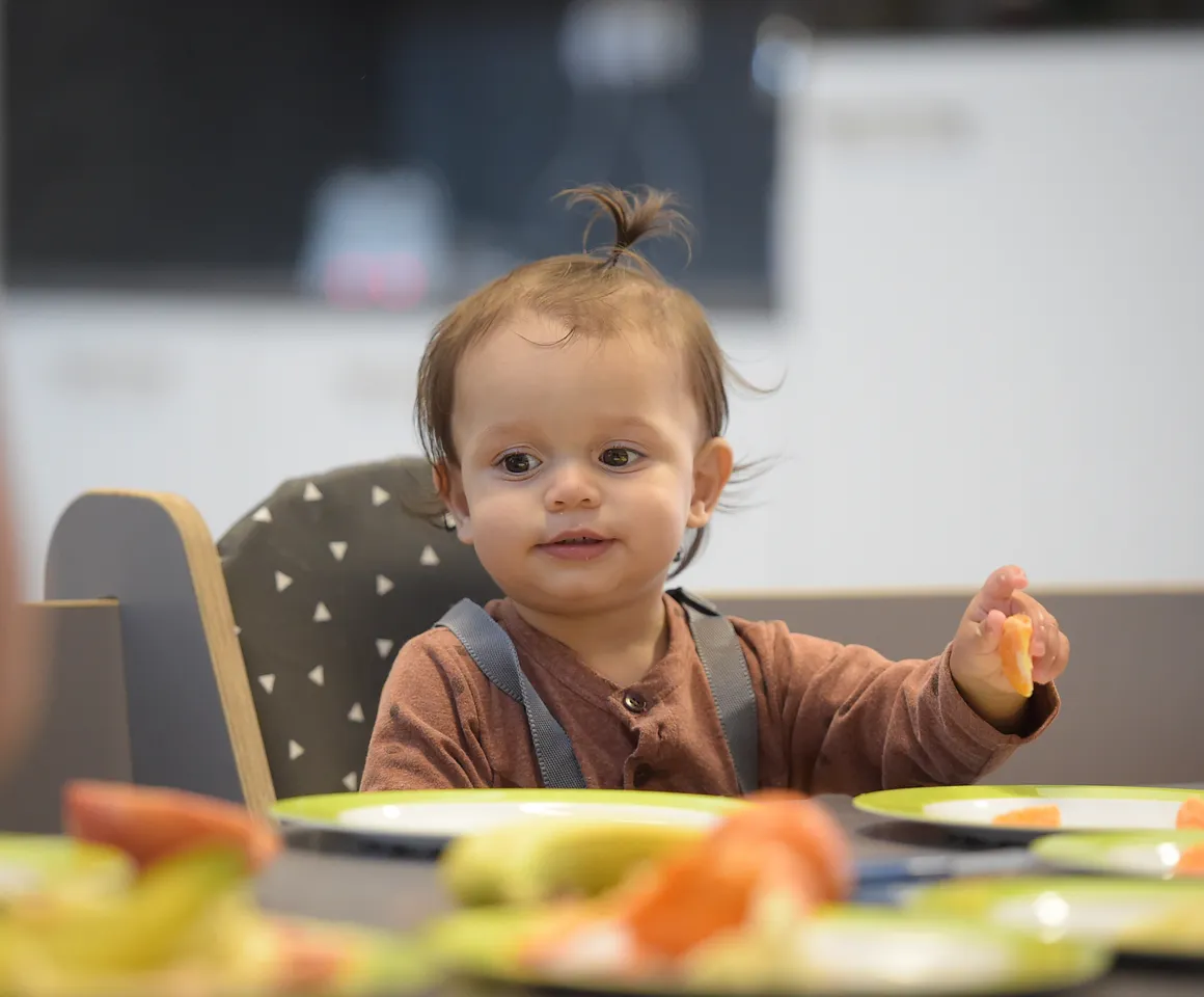 Baby is lekker aan het eten tijdens de lunch bij kinderopvang Kind&co ludens