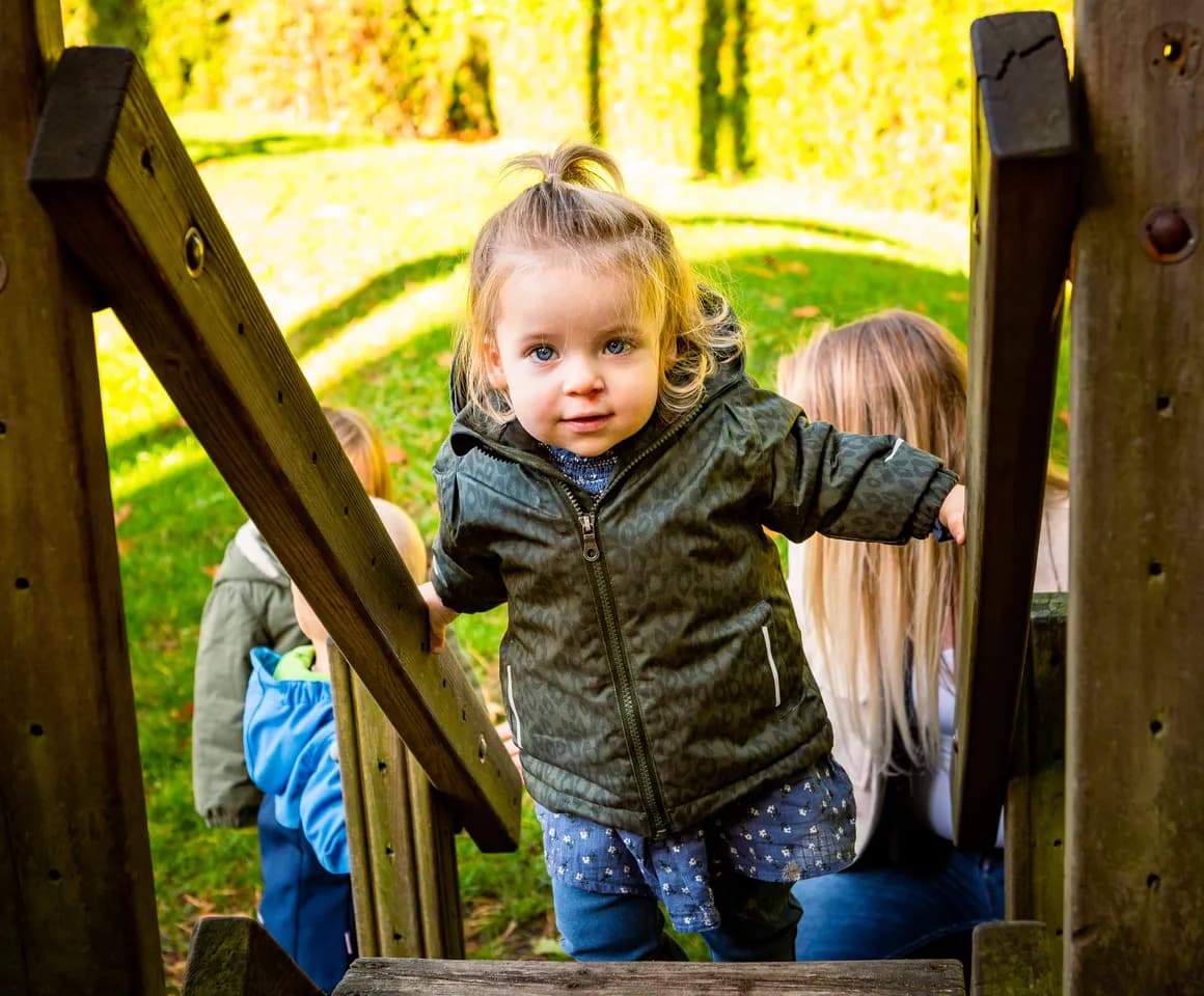 Kind speelt buiten op een speeltoestel bij kinderopvang Kind&co ludens