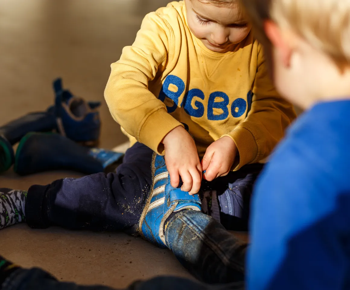 Kinderen doen samen hun schoenen uit bij kinderopvang Kind&co ludens