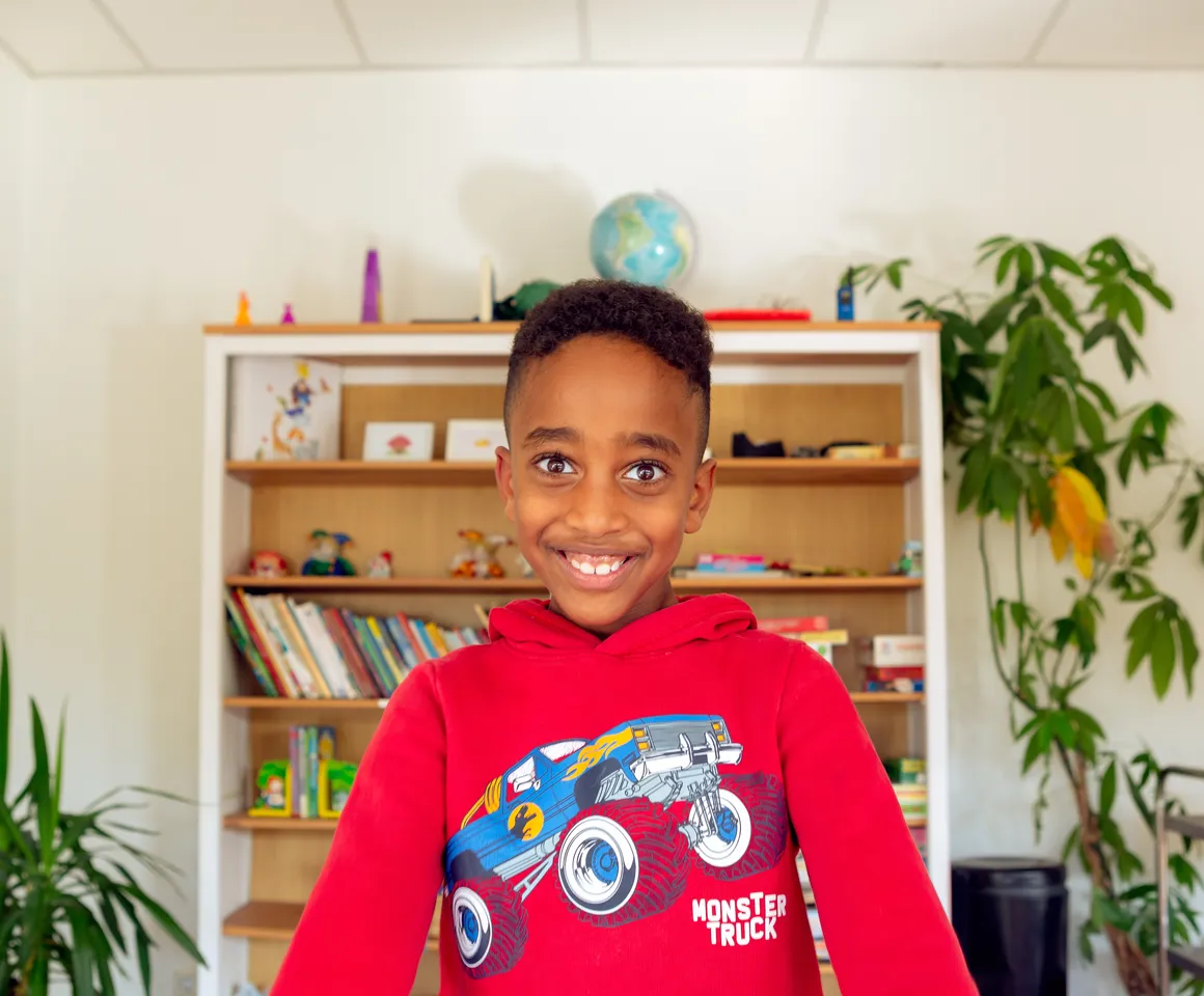 Kind bij de BSO lacht heel blij en straalt bij kinderopvang Kind&co ludens