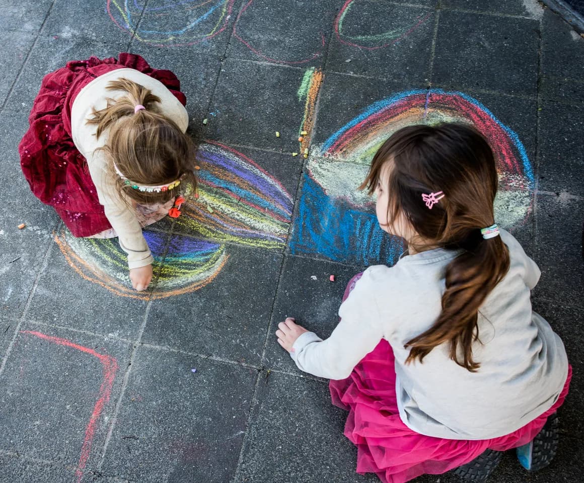 Kinderen maken een tekening met stoepkrijt bij buitenschoolse opvang Maanvis, kinderopvang Kind&co Ludens