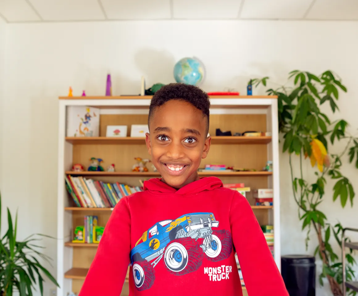 Kind bij de BSO lacht heel blij en straalt bij kinderopvang Kind&co ludens