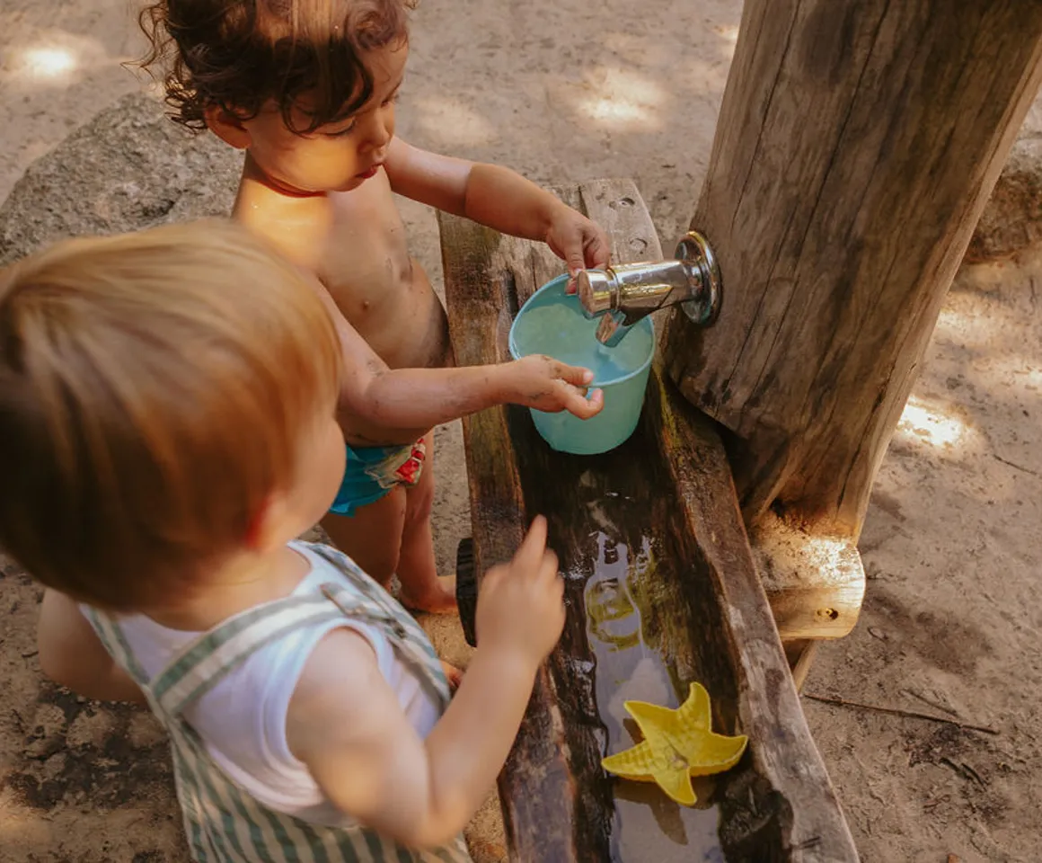Kinderen spelen buiten met modder en water bij kinderopvang Kind&co ludens
