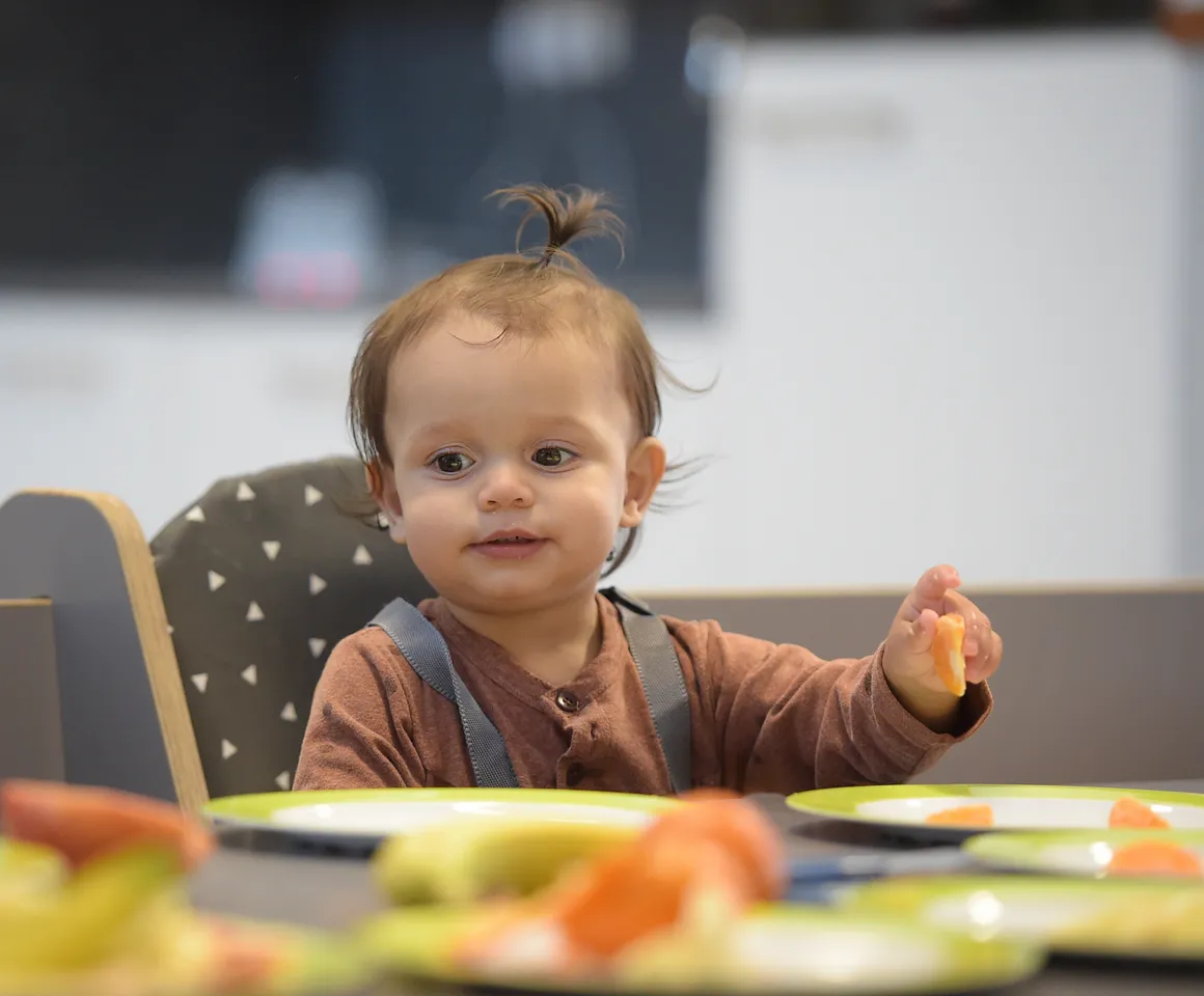 Baby is lekker aan het eten tijdens de lunch bij kinderopvang Kind&co ludens