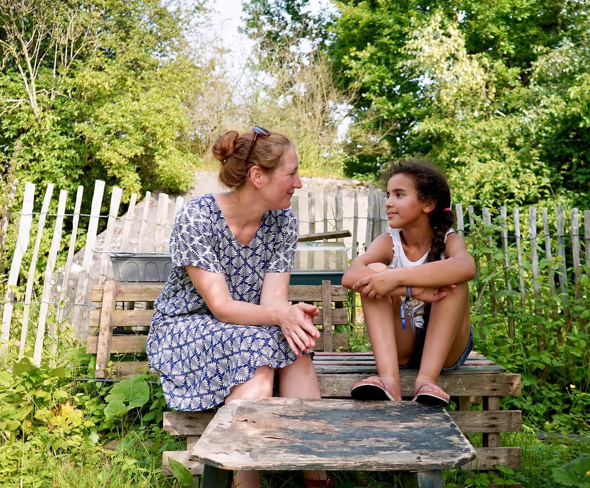 Kind bij de BSO praat buiten samen met de pedagogisch medewerker bij kinderopvang Kind&co ludens