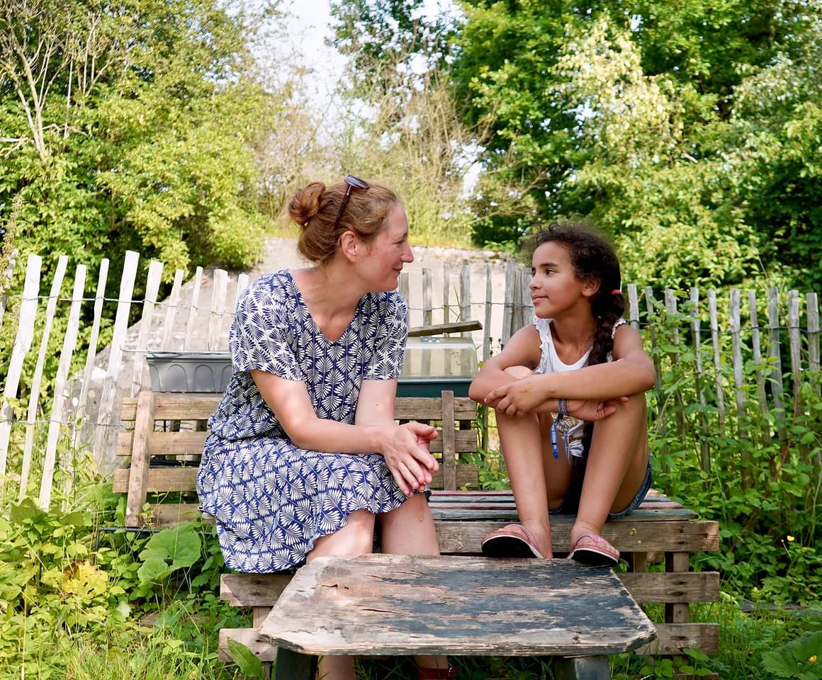 Kind bij de BSO praat buiten samen met de pedagogisch medewerker bij kinderopvang Kind&co ludens