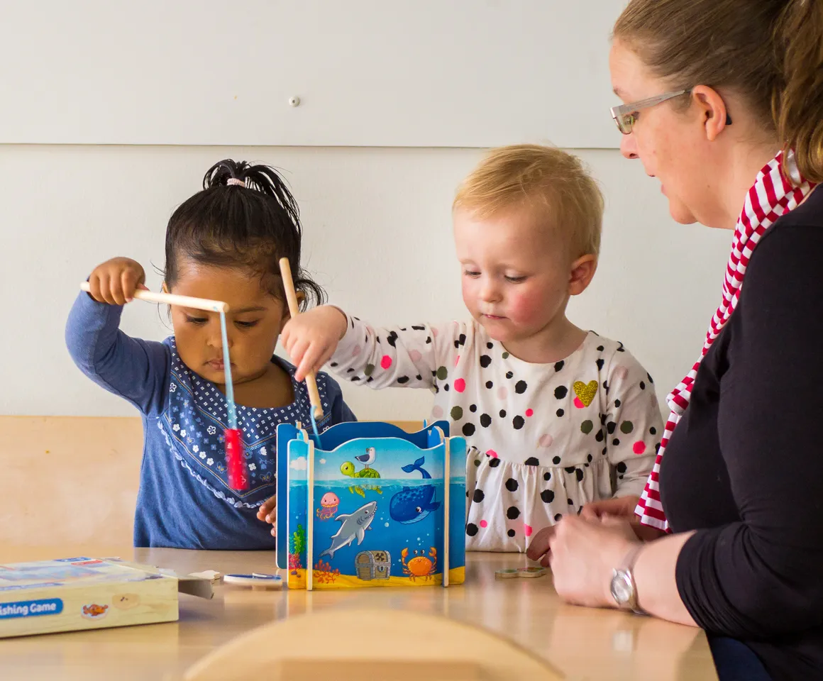 Kinderen spelen samen "Vissen" onder begeleiding van een pedagogisch medewerker bij kinderopvang Kind&co ludens