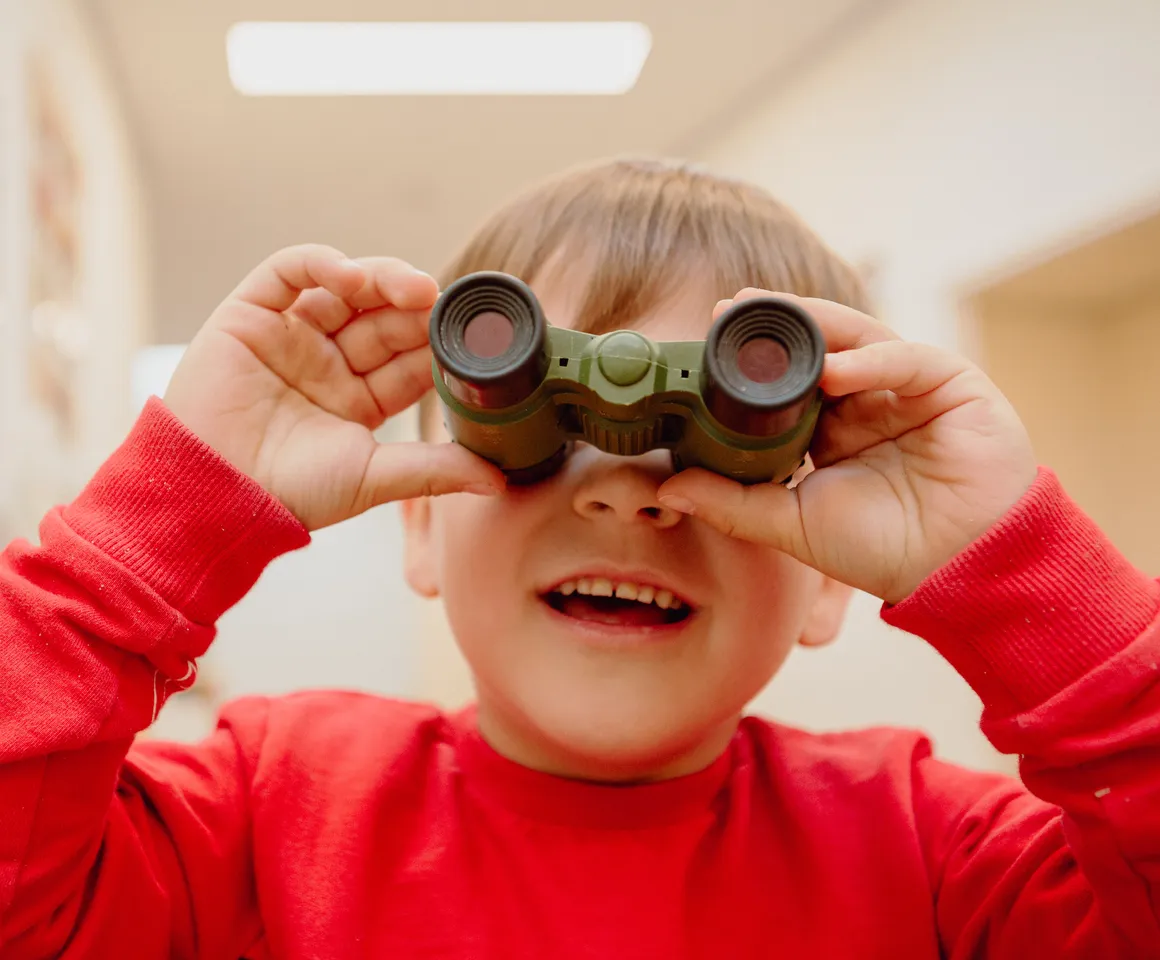 Kind kijkt door een verrekijker bij een Peutergroep van kinderopvang Kind&co ludens
