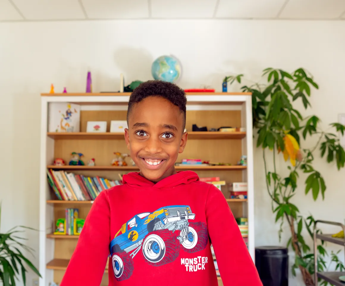 Kind bij de BSO lacht heel blij en straalt bij kinderopvang Kind&co ludens