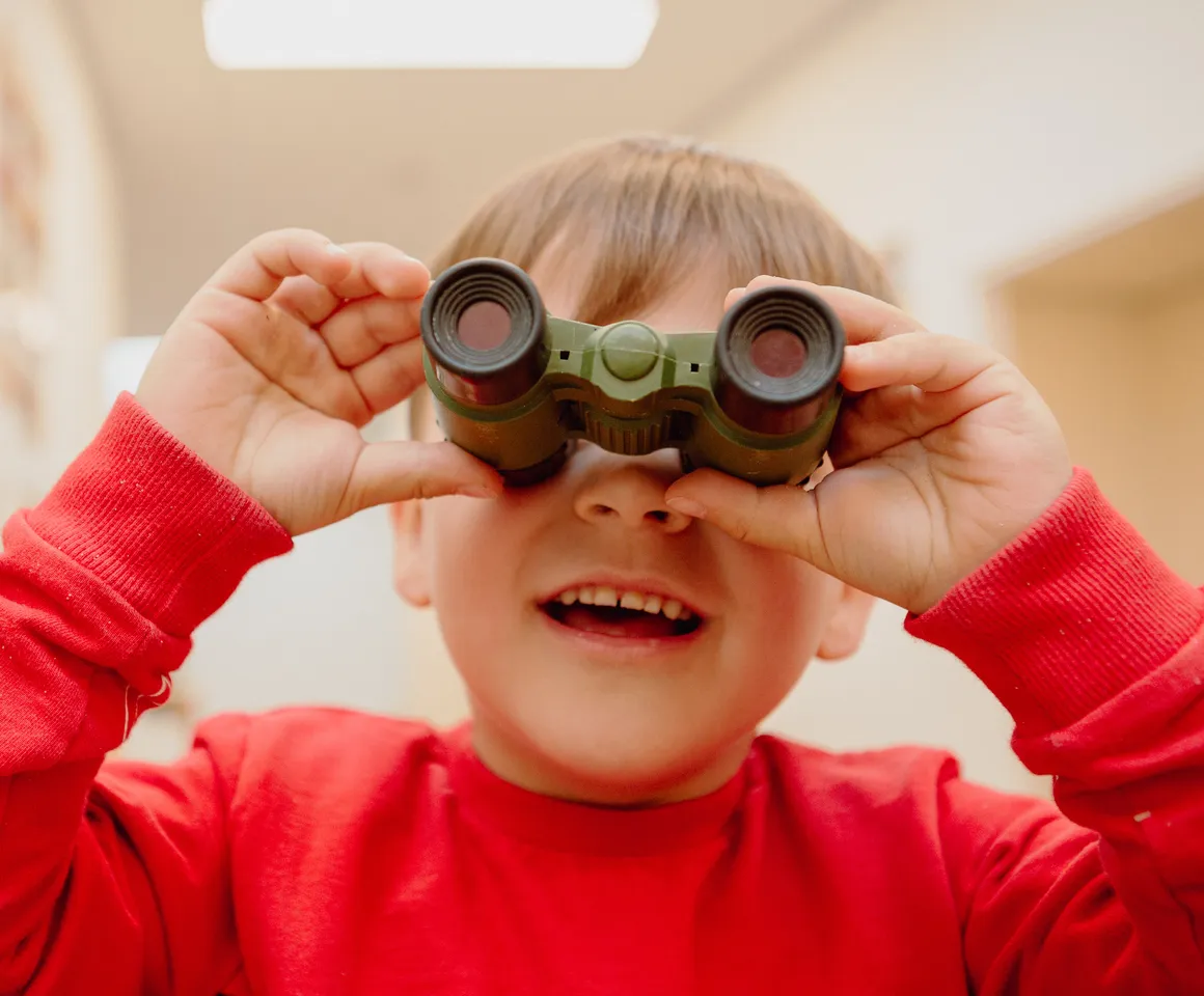 Kind kijkt door een verrekijker bij een Peutergroep van kinderopvang Kind&co ludens