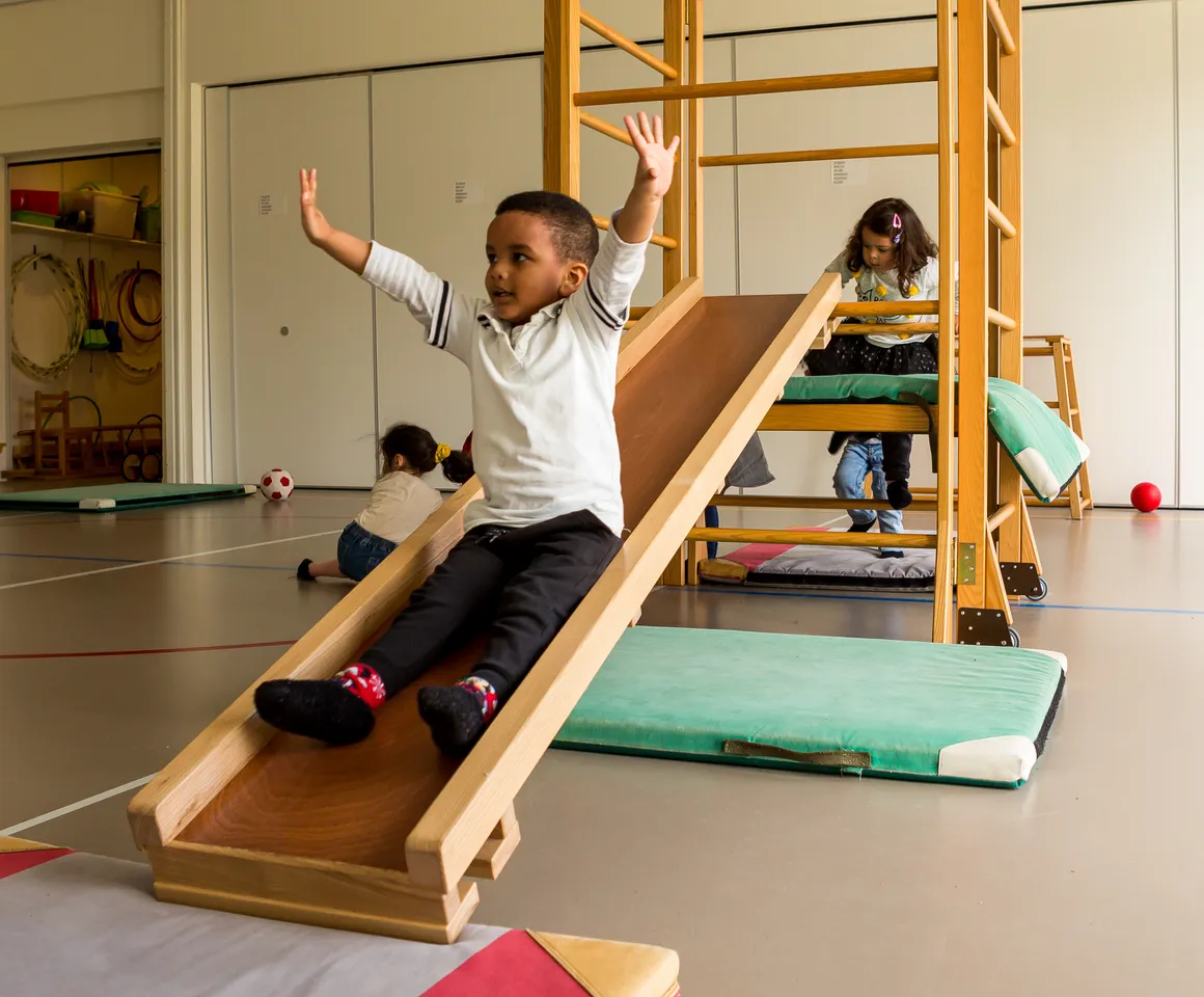 Kinderen klimmen en glijden in gymzaal bij kinderopvang Kind&co ludens
