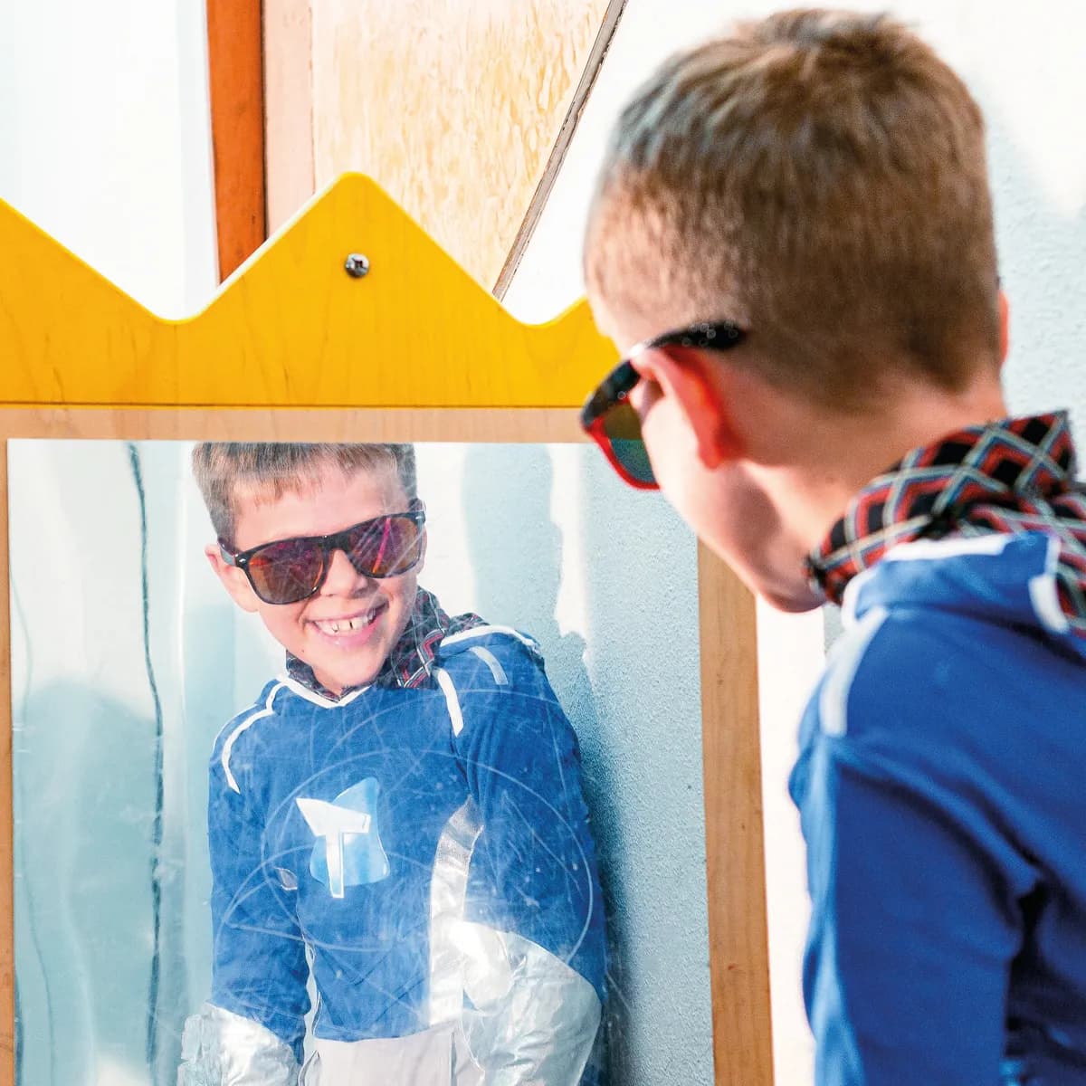 Kind op de BSO heeft veel plezier tijdens een verkleedpartij bij het kijken in de spiegel van kinderopvang Kind&co ludens