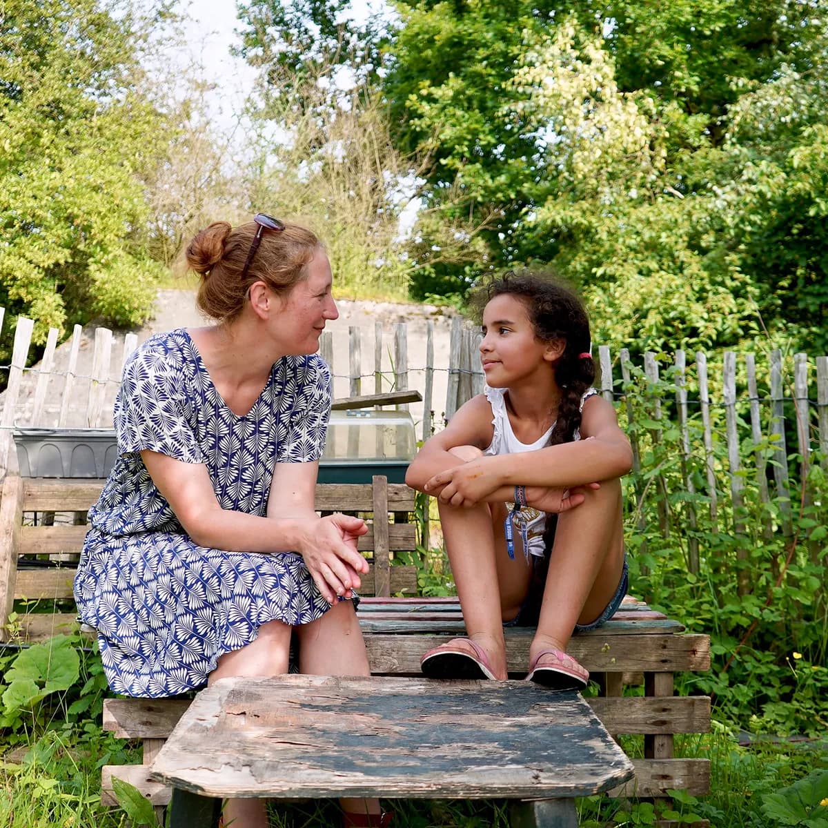 Kind bij de BSO praat buiten samen met de pedagogisch medewerker bij kinderopvang Kind&co ludens