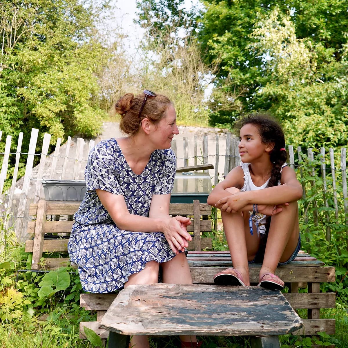 Kind bij de BSO praat buiten samen met de pedagogisch medewerker bij kinderopvang Kind&co ludens