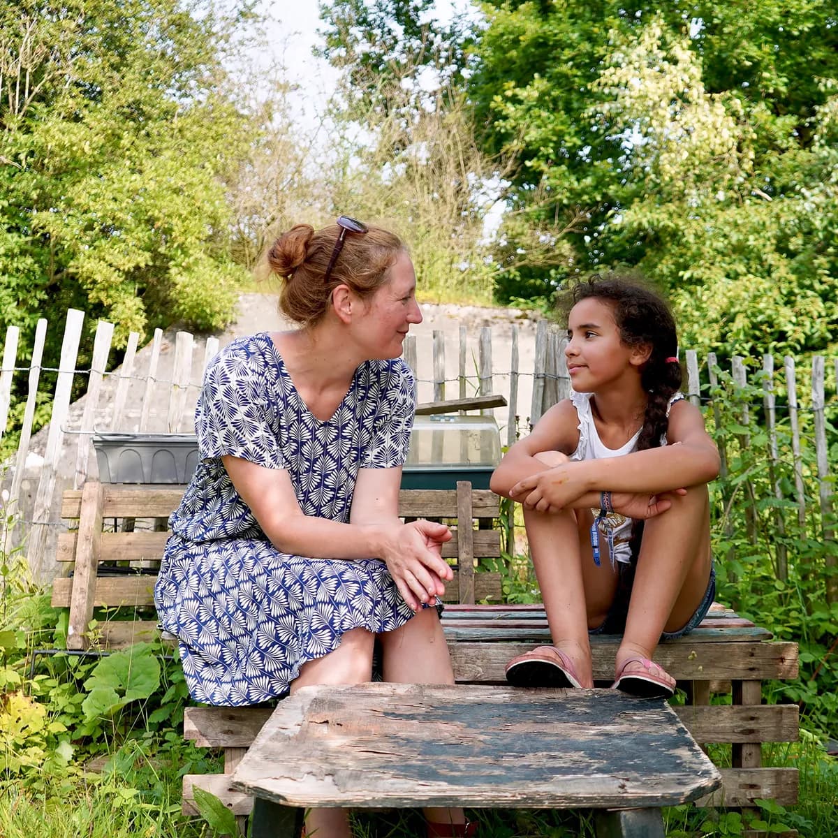 Kind bij de BSO praat buiten samen met de pedagogisch medewerker bij kinderopvang Kind&co ludens