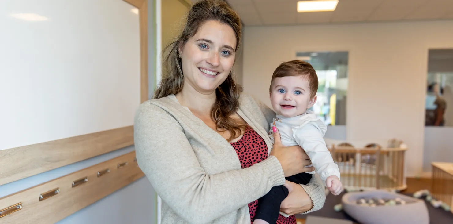 Baby wordt geknuffeld door pedagogisch medewerker bij kinderopvang Kind&co ludens
