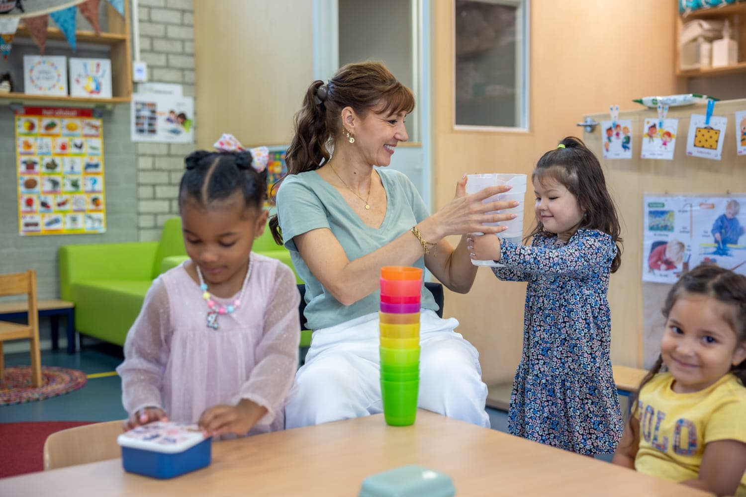Kinderen schenken drinken in samen met pedagogisch medewerker bij kinderopvang Kind&co ludens