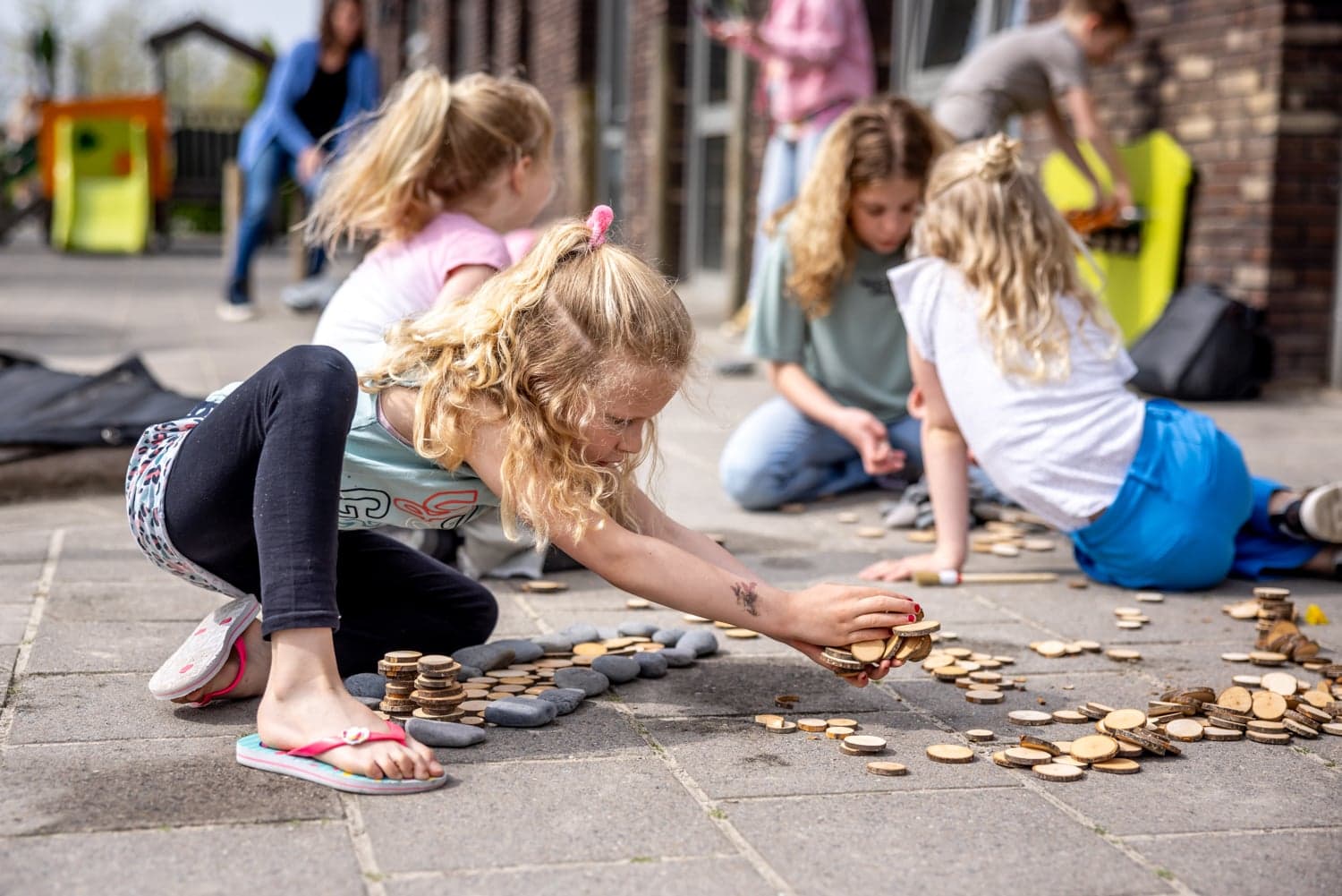 Kinderen spelen buiten op de grond bij kinderopvang Kind&co ludens